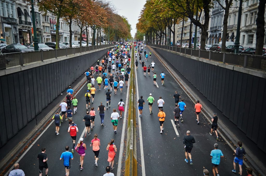 Aerial view of runners in a city marathon on a long tree-lined road