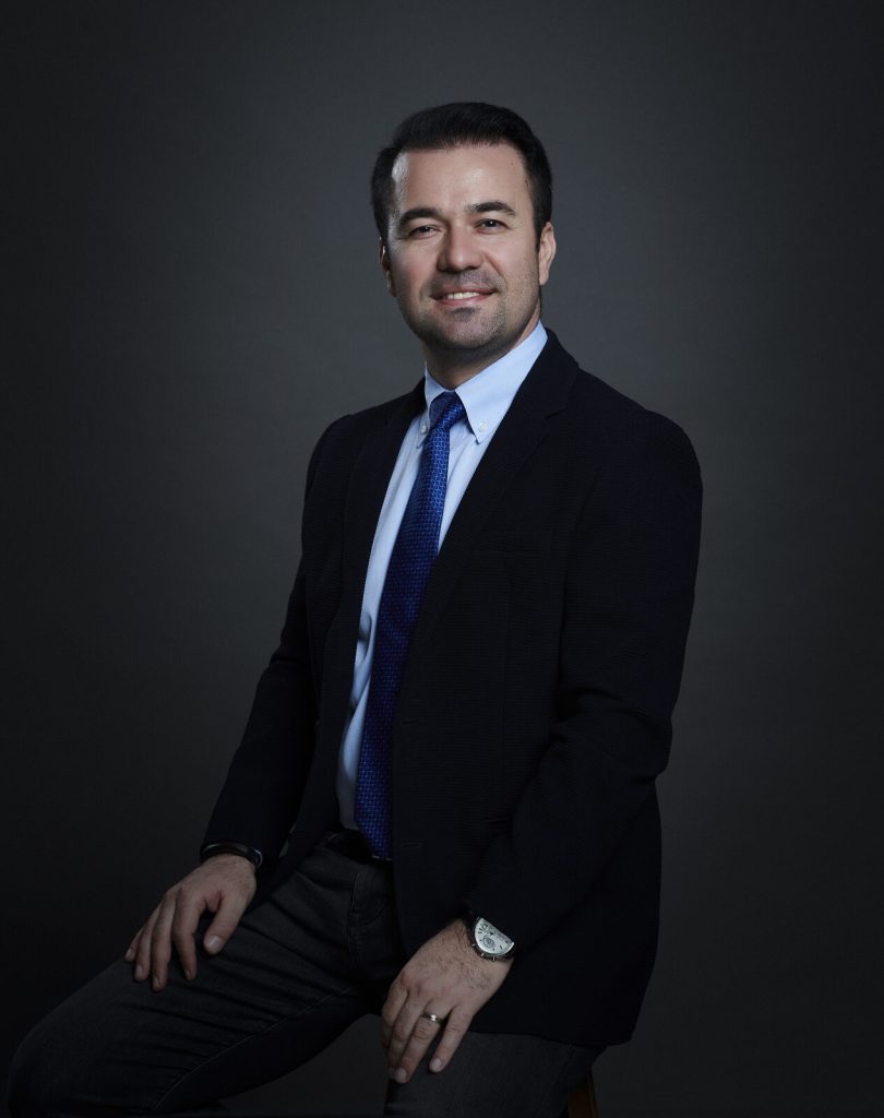 Gökhan Salmanoğlu seated, in a dark suit